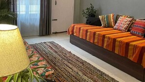 Une chambre à coucher avec un lit, une fenêtre avec des rideaux, une porte et une plante.