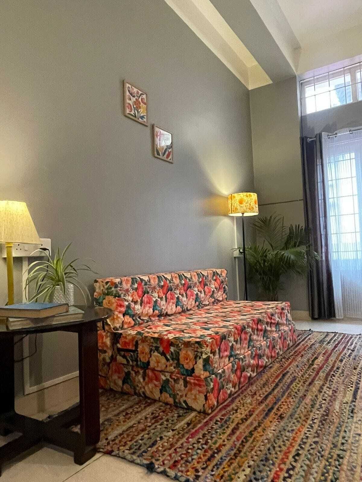 A room with a bed, a lamp, a plant, and a window.