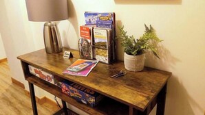 A wooden table with a lamp, a plant, and a magazine rack with travel books. - Inverness City Centre Apartment With elevator (Inverness)