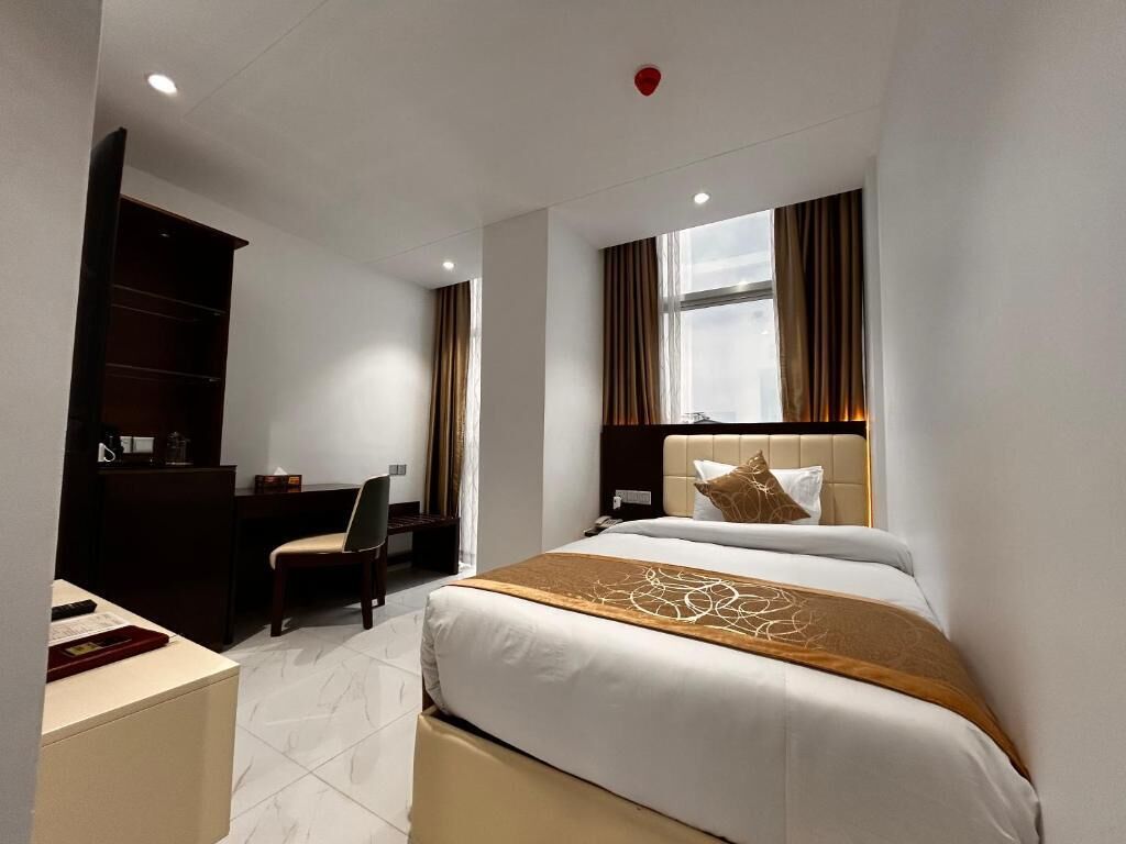 A hotel room with a bed, desk, chair, and wardrobe.