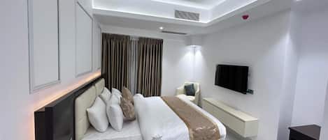 A modern bedroom with a bed, bedside table, TV, and a built-in bench.