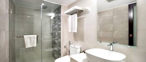 A modern bathroom with a glass shower enclosure, a white sink, and a large mirror.