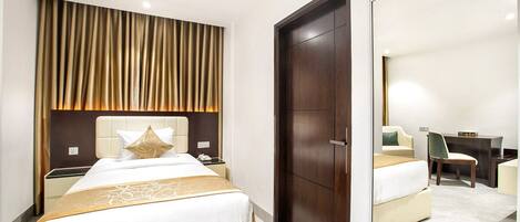 A hotel room with a bed, bedside table, mirror, and a wardrobe.