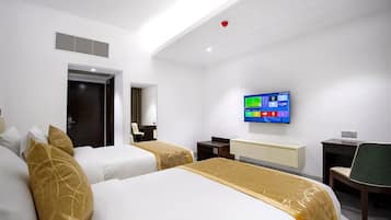 A hotel room with two beds, a desk, a chair, a television, and a door.