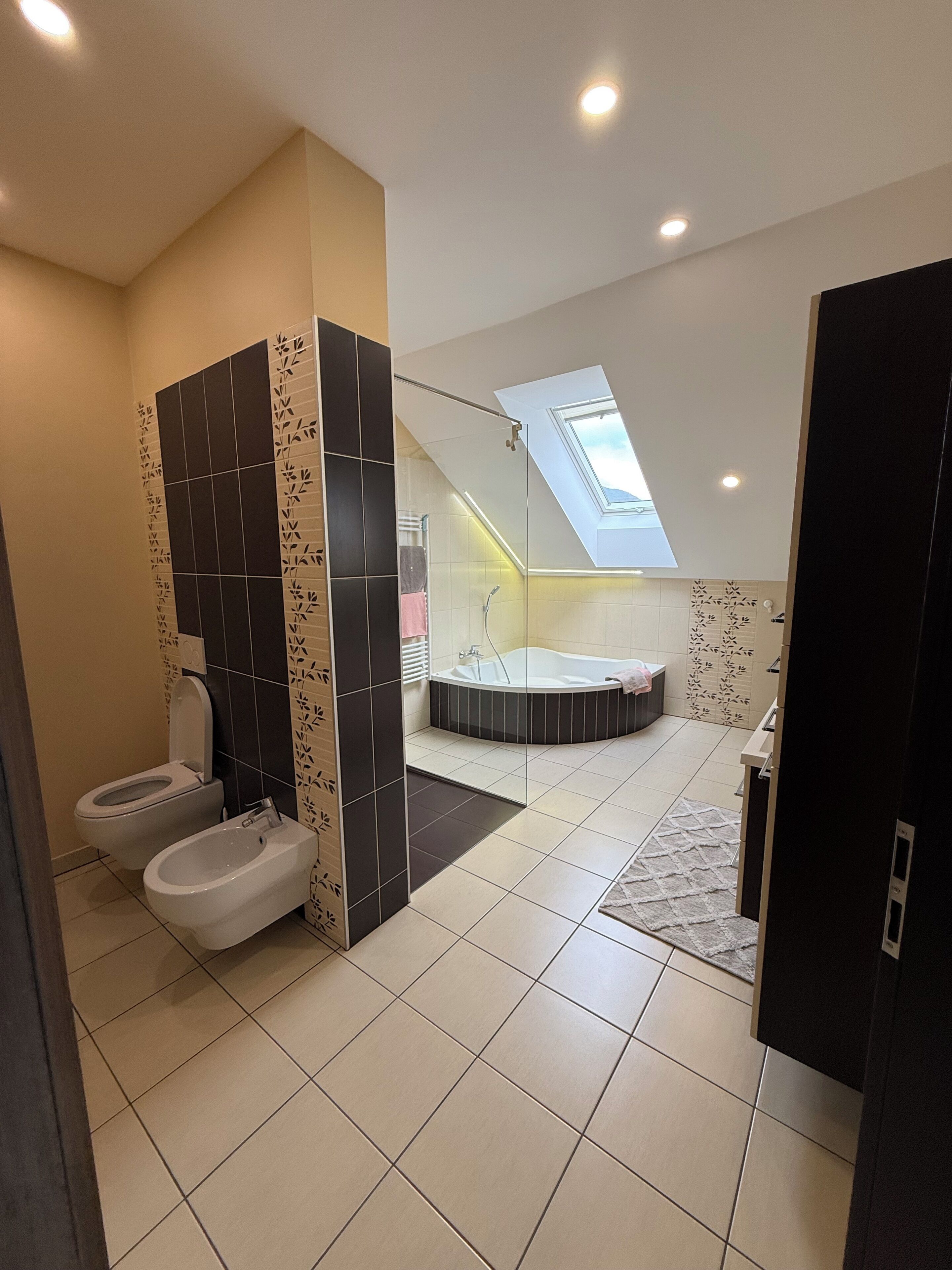 A modern bathroom with a toilet, bidet, and bathtub.