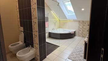 A modern bathroom with a toilet, bidet, and bathtub.