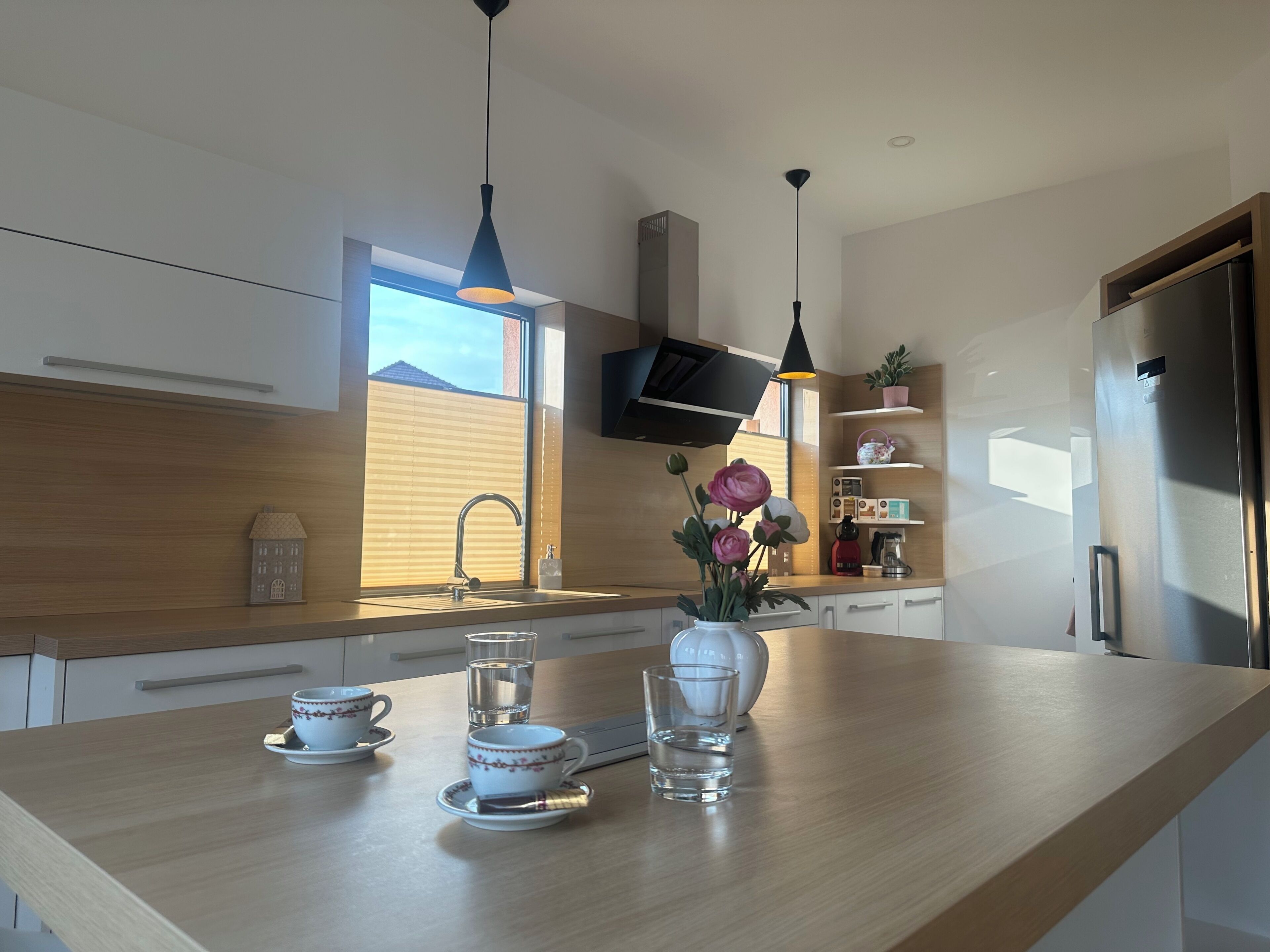 Una cocina moderna con encimera de madera, un lavamanos integrado, un refrigerador de acero inoxidable y una ventana que ofrece luz natural.