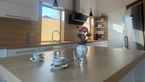 A modern kitchen with a wooden countertop, a built-in sink, a stainless steel refrigerator, and a window providing natural light. - Spacious Family Villa – 4BR, 3Bath Near Airport (Cerklje na gorenjskem)