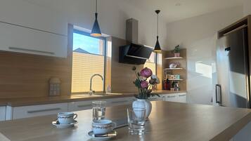 Una cocina moderna con encimera de madera, un lavamanos integrado, un refrigerador de acero inoxidable y una ventana que ofrece luz natural.