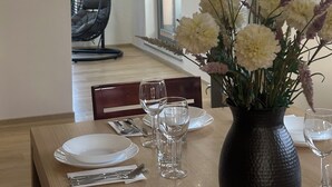 A dining area with a table set for two, a hanging chair, and a vase with flowers. - Spacious Family Villa – 4BR, 3Bath Near Airport (Cerklje na gorenjskem)