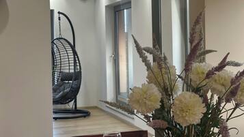 Un área de comedor con una mesa preparada para dos personas, un sillón colgante y un florero con flores.