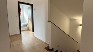 A modern interior with a wooden floor, a staircase with a glass railing, and a doorway leading to another room. - Spacious Family Villa – 4BR, 3Bath Near Airport (Cerklje na gorenjskem)