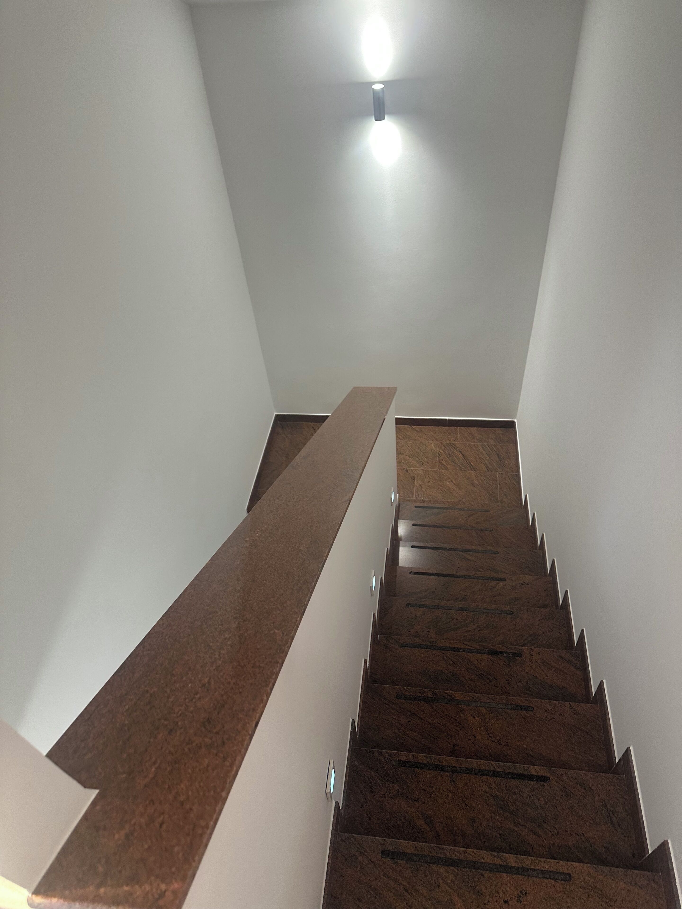 A staircase with wooden steps and a handrail, leading to a landing with a light fixture.