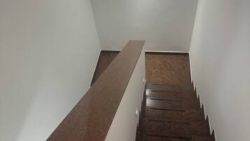 A staircase with wooden steps and a handrail, leading to a landing with a light fixture.