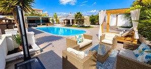 Une piscine avec des chaises longues et un espace de repos abrité.
