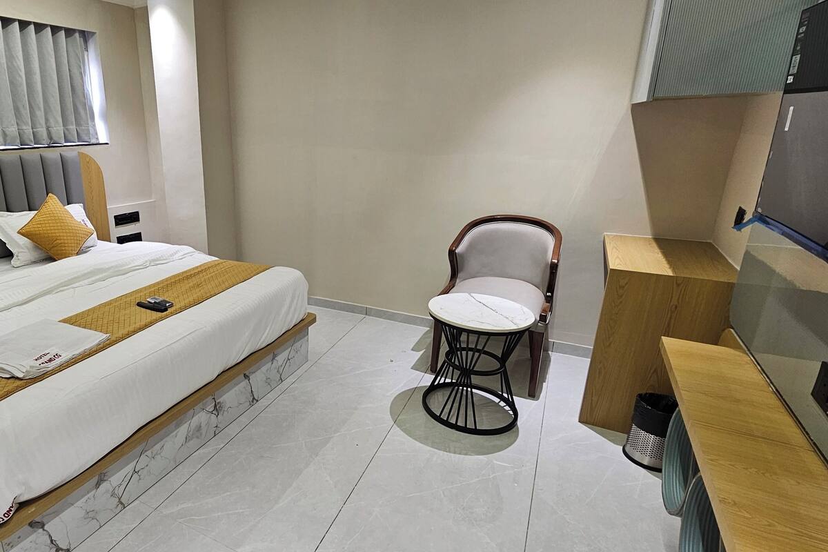 Una habitación de hotel con cama, mesita de noche, silla y televisión.