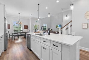 A modern kitchen with white cabinetry, a large island, and pendant lighting. - Villa Mojito Main | Gated Lakefront Home (St. Augustine)