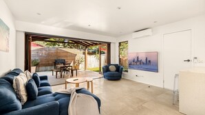 A modern living room with a sofa, coffee table, and a TV mounted on the wall. - Palm Beach Escape Steps From Sand (Gold Coast)
