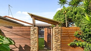 A wooden gate with a stone archway leading to a covered patio area. - Palm Beach Escape Steps From Sand (Gold Coast)
