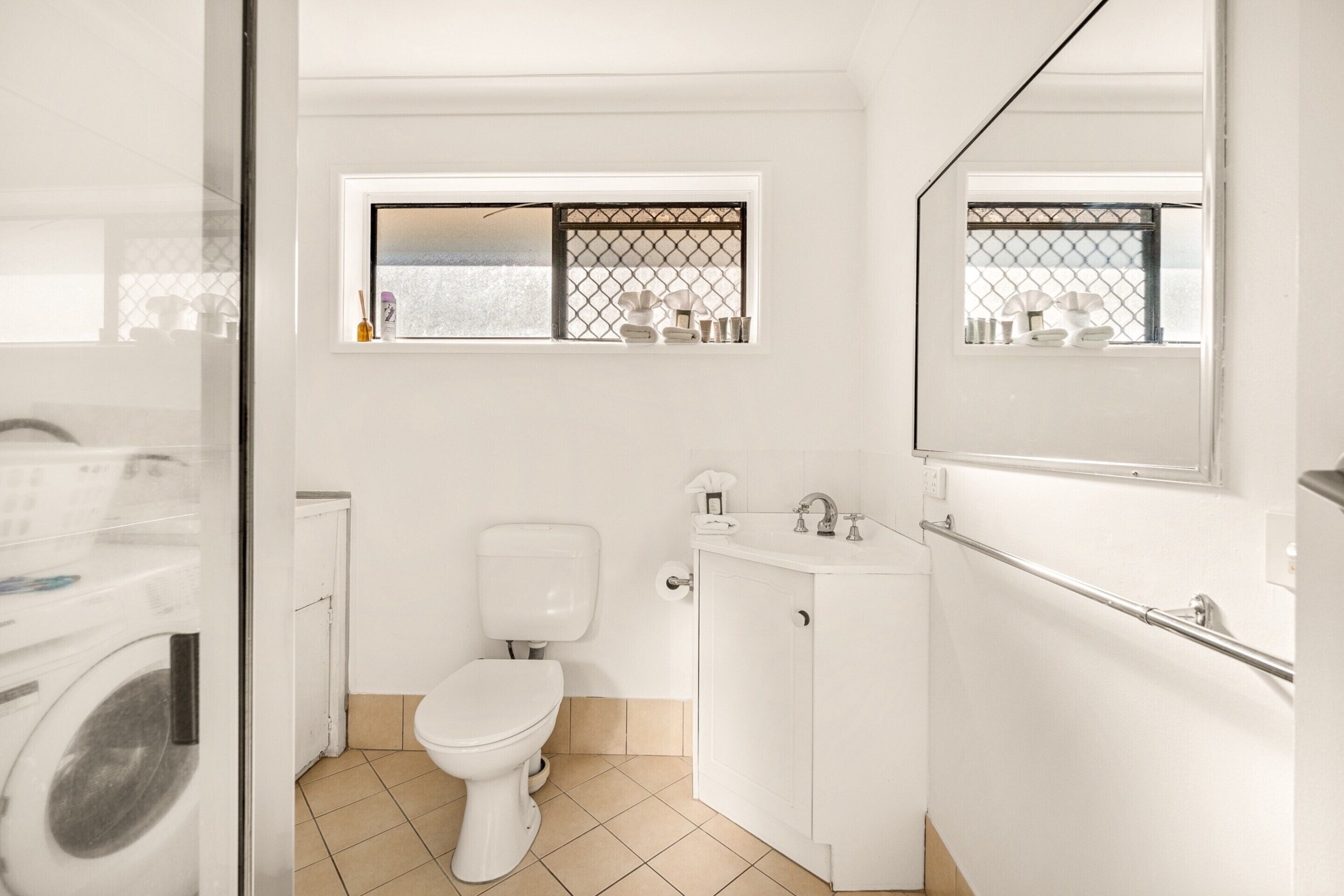 Un baño moderno con inodoro, lavamanos y ventana con vistas.