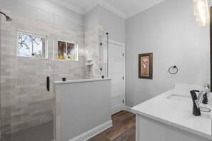 Une salle de bain moderne avec une douche, un meuble-lavabo avec un miroir et une fenêtre.