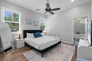A bedroom with a bed, nightstands, a ceiling fan, a large window, and a view of the outdoors. - Villa Mojito Lakefront Home + APTs Sleeps 24 (St. Augustine)