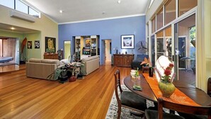 Uma sala de estar espaçosa com piso de madeira, uma área de jantar com mesa e cadeiras, e uma grande janela com vista.