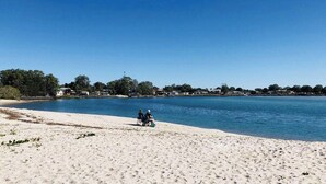 Uma praia com vista clara para o mar e uma fileira de casas ao fundo.