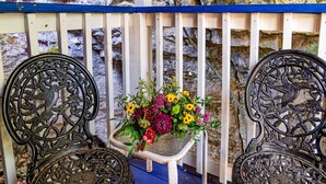 A bench with intricate metalwork and a planter with flowers. - Cliff Cottage Inn - Colette Queen Jacuzzi Suite (Eureka Springs)