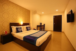 A hotel room with a large bed, bedside tables, a desk, and a TV mounted on the wall. - Hotel Global Star (New Delhi)