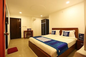 A bedroom with a bed, a desk, a wardrobe, and a bedside table. - Hotel Global Star (New Delhi)