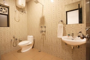 Een badkamer met toilet, douche, wastafel en een spiegel.
