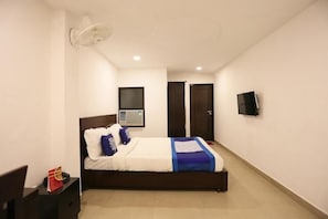 Een hotelkamer met een bed, een televisie, een ventilator en een raam.
