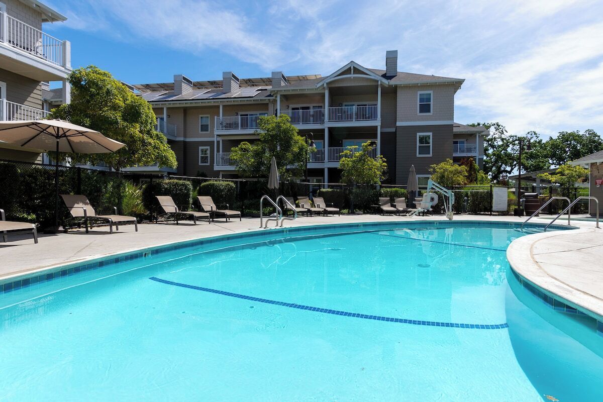 A swimming pool with lounge chairs and a building with balconies in the background.