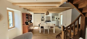 A spacious kitchen with wooden beams, a dining area with a table and chairs, and a staircase. - House with a view of the mountains, St. Jacques des Blats, Lioran. (Saint-Jacques-des-Blats)