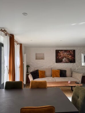 A living room with a sofa, a dining table, and a painting on the wall. - T3, Sea view pool and jacuzzi, Le Pouldu (Clohars-Carnoët)