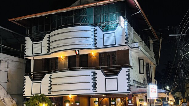 A multi-story building with a modern architectural design, featuring balconies and a gated entrance.