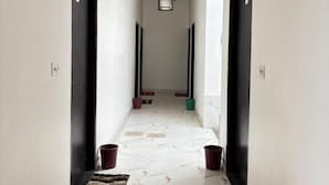 Un couloir doté d’un sol en marbre, de portes noires et de touches de couleur orange au plafond.