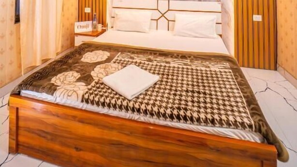 Une chambre avec un lit en bois, un ventilateur de plafond et une tête de lit en marbre.