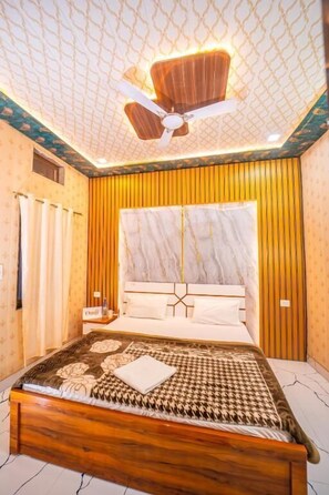 Une chambre avec un lit en bois, un ventilateur de plafond et une tête de lit en marbre.