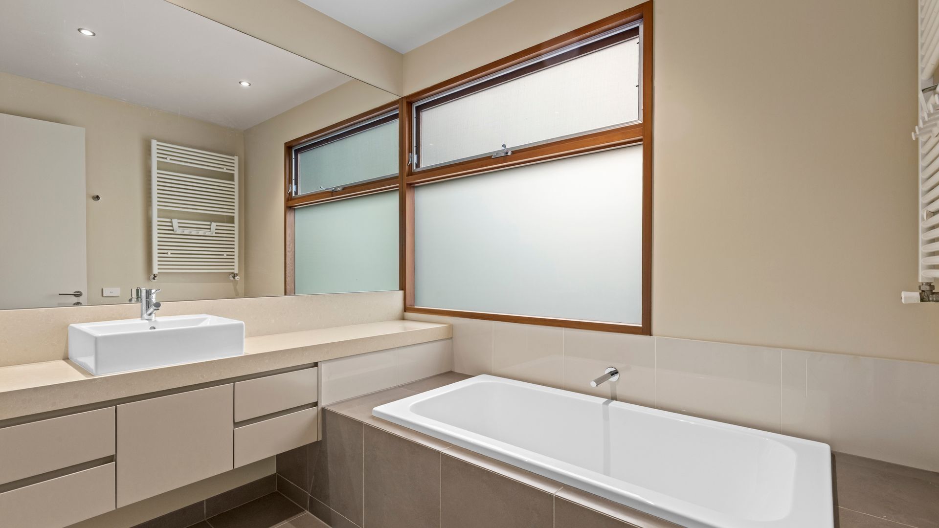 Een moderne badkamer met een groot raam, een wastafel, een bad en een spiegel.