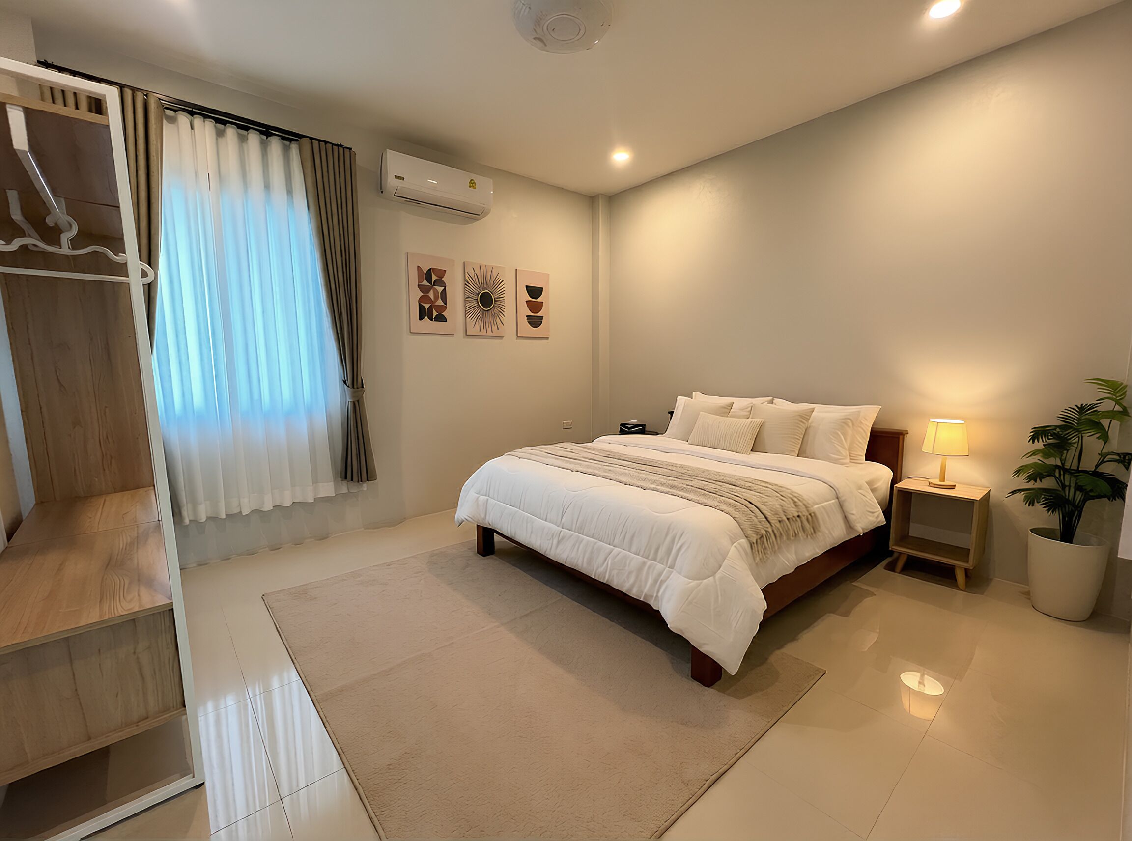 Un dormitorio con cama, mesitas de noche, aire acondicionado instalado en la pared, ventana con cortinas y una planta en maceta.