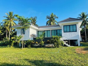 A modern two-story house with a flat roof, large windows, and a well-maintained lawn.