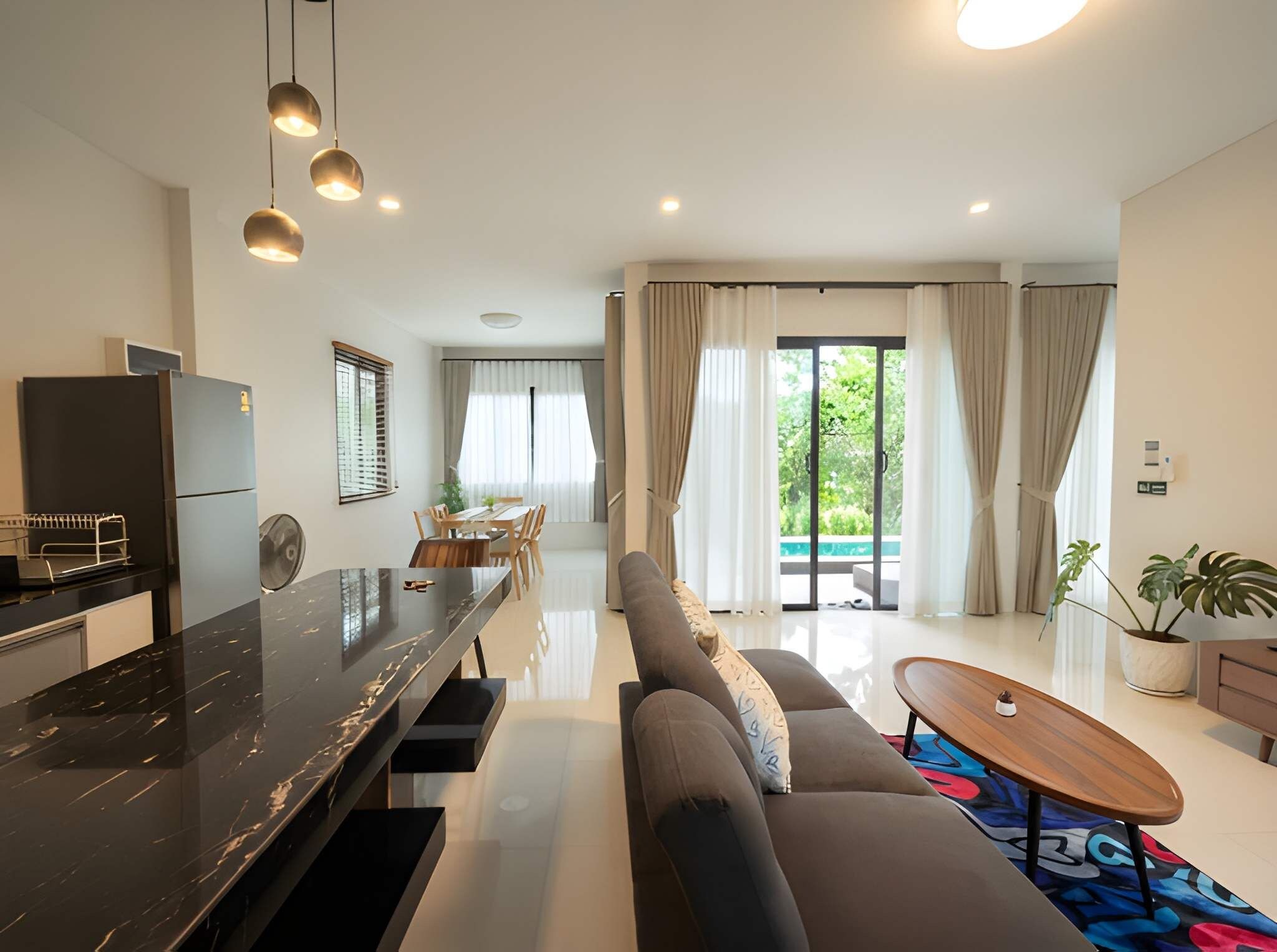 A modern living room with a black marble bar, a sofa, a coffee table, and a dining area with a table and chairs.