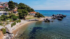 A coastal area with clear waters, rocky shoreline, and buildings with red roofs.