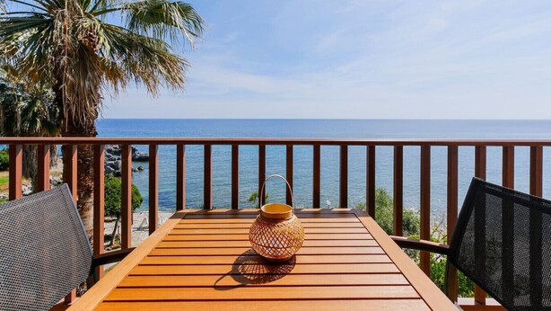 A wooden deck with a table, chairs, and a decorative vase.