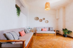 Un salon avec deux canapés, un luminaire suspendu et un objet décoratif fixé au mur.
