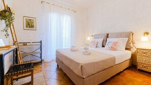 A neatly arranged bedroom with a bed, bedside tables, a desk, and a chair.