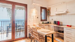 A kitchen with a view of the sea, a dining area with wicker chairs, and a balcony with a table and chairs.