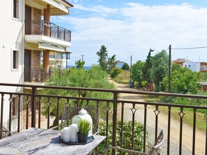 Un balcone con tavolo, piante in vaso e vista su una zona residenziale con case e vegetazione.